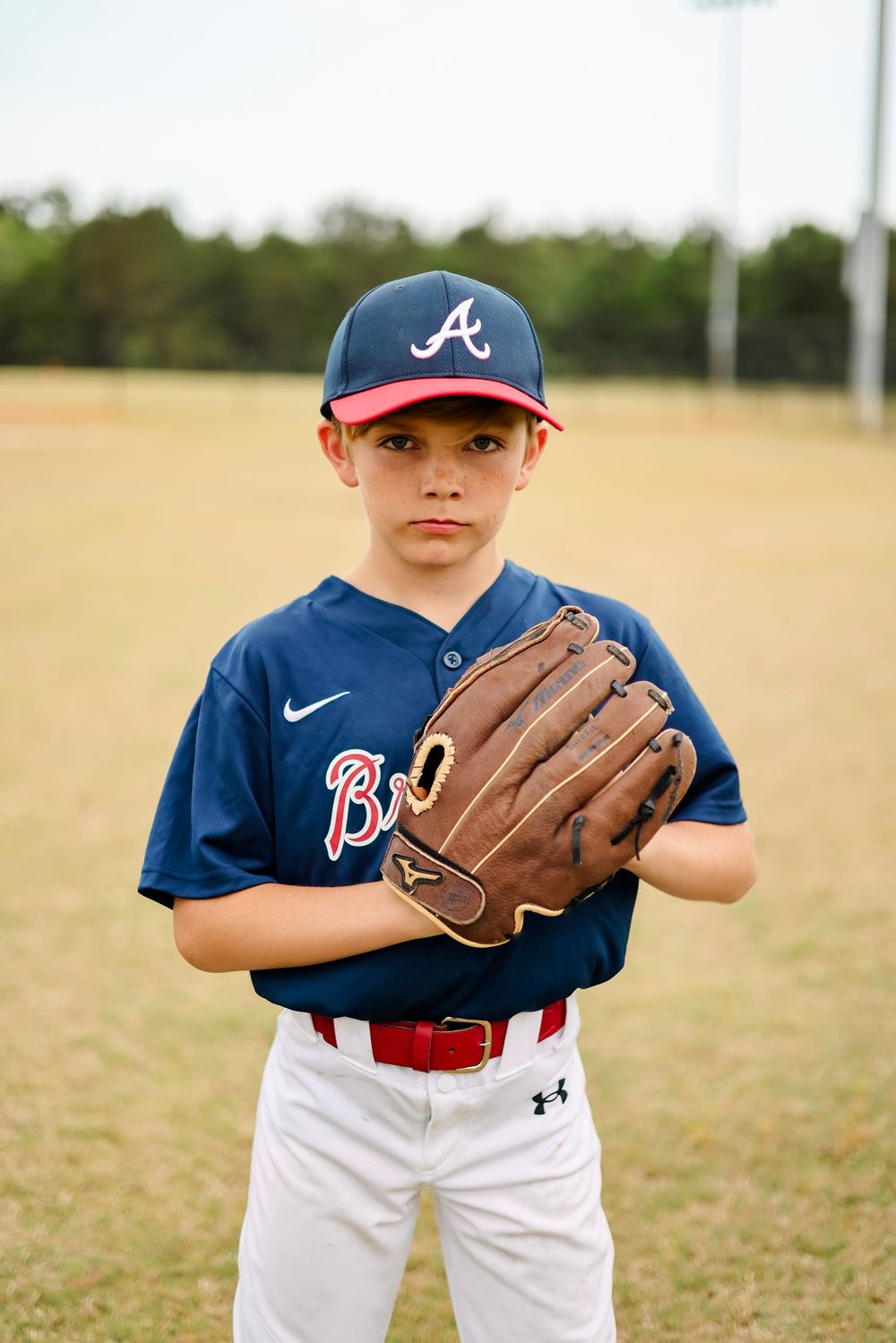 Three sequential baseball photos show a player in a navy and white uniform with a brown leather glove on a sunny field.