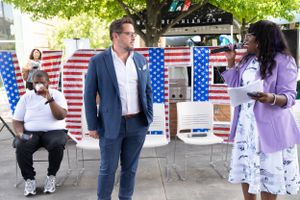Attendees engage in conversation at a political event with American flags in the background.