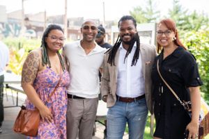 Group of friends smile together for a photo at an outdoor event.