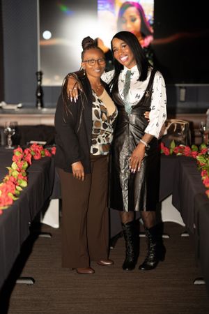 Two people posing together at event wearing contrasting black and white outfits.