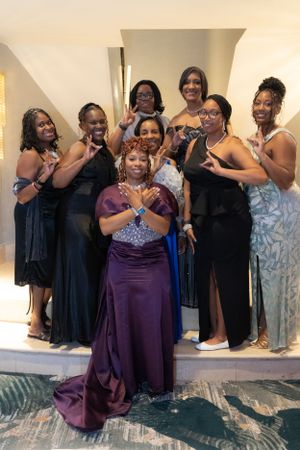 A group poses together in formal evening wear at an elegant event.