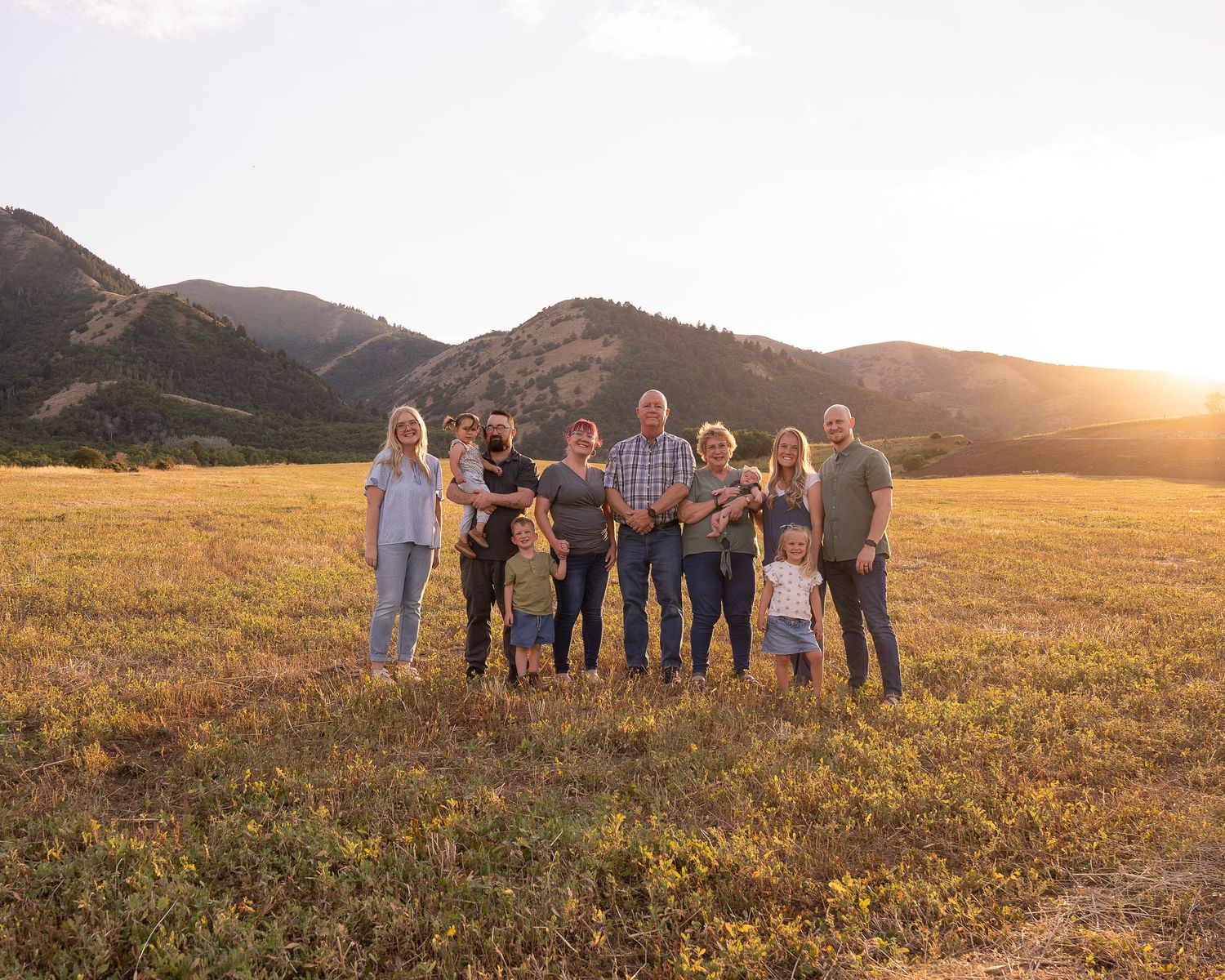 Family of four embracing on top of rock smiling at Tony's Grove in logan canyon. Fall colors are present. Family session in Logan Canyon.