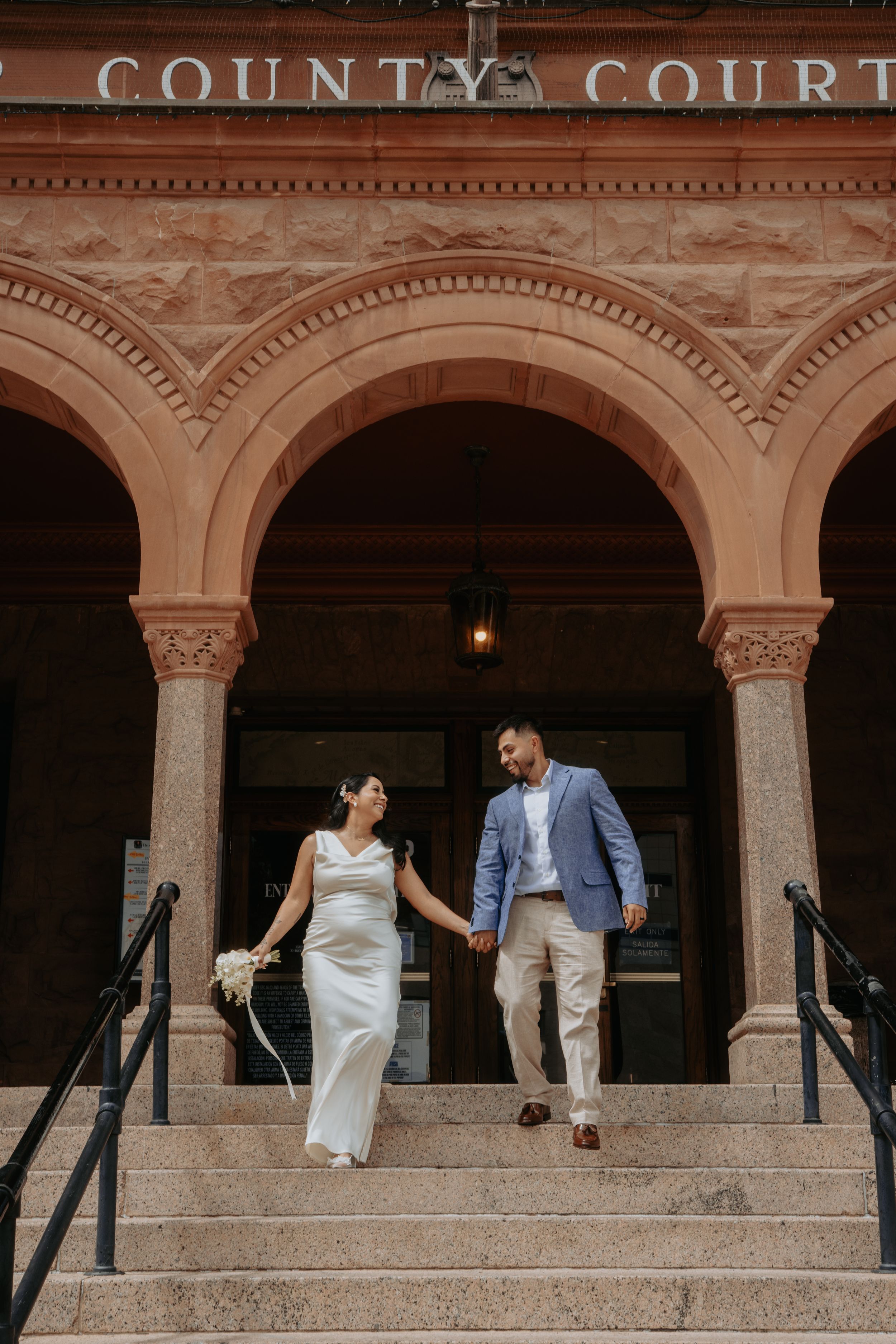 Two people share a romantic moment while standing in stone archways at Philbrook Museum in Tulsa, Oklahoma.