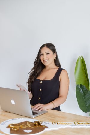 Professional working on laptop computer with monstera plant and natural light in modern office setting.