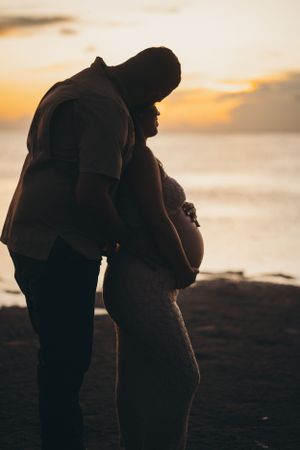Silhouette of two people embracing on a beach at sunset.