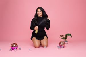 Studio portrait with pink background featuring holiday decorations and ornaments.