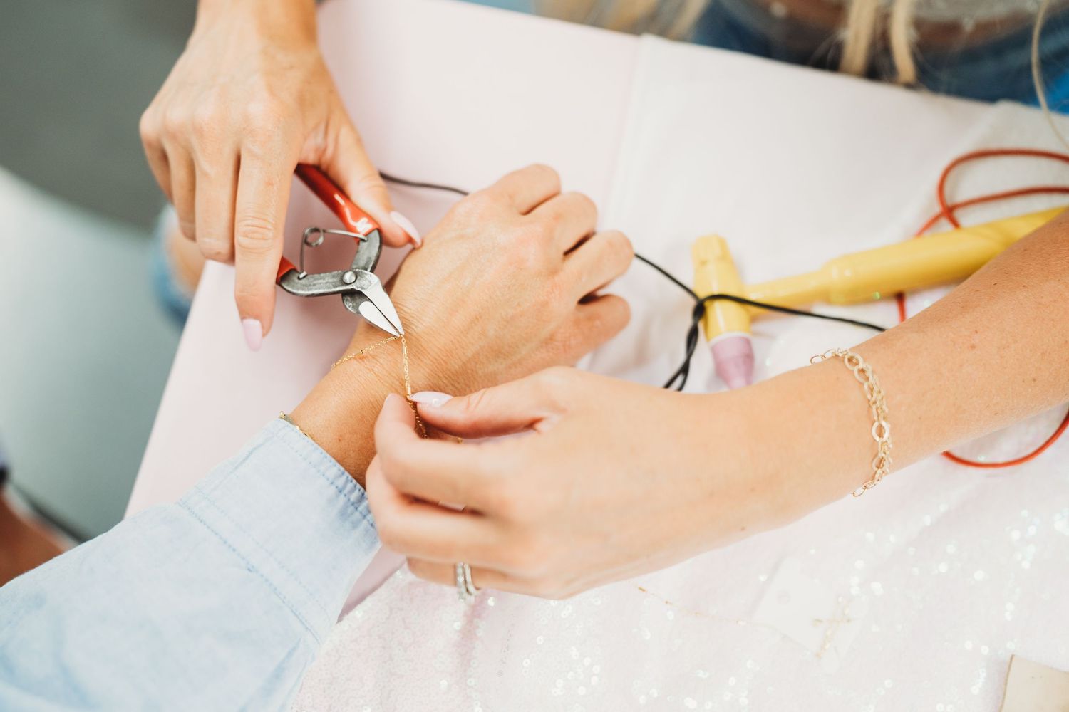 Hands working on a creative project with various materials on a light surface.