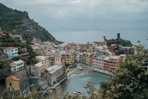 A high up view of Vernazza in Cinque Terre, Italy with mountains and water.