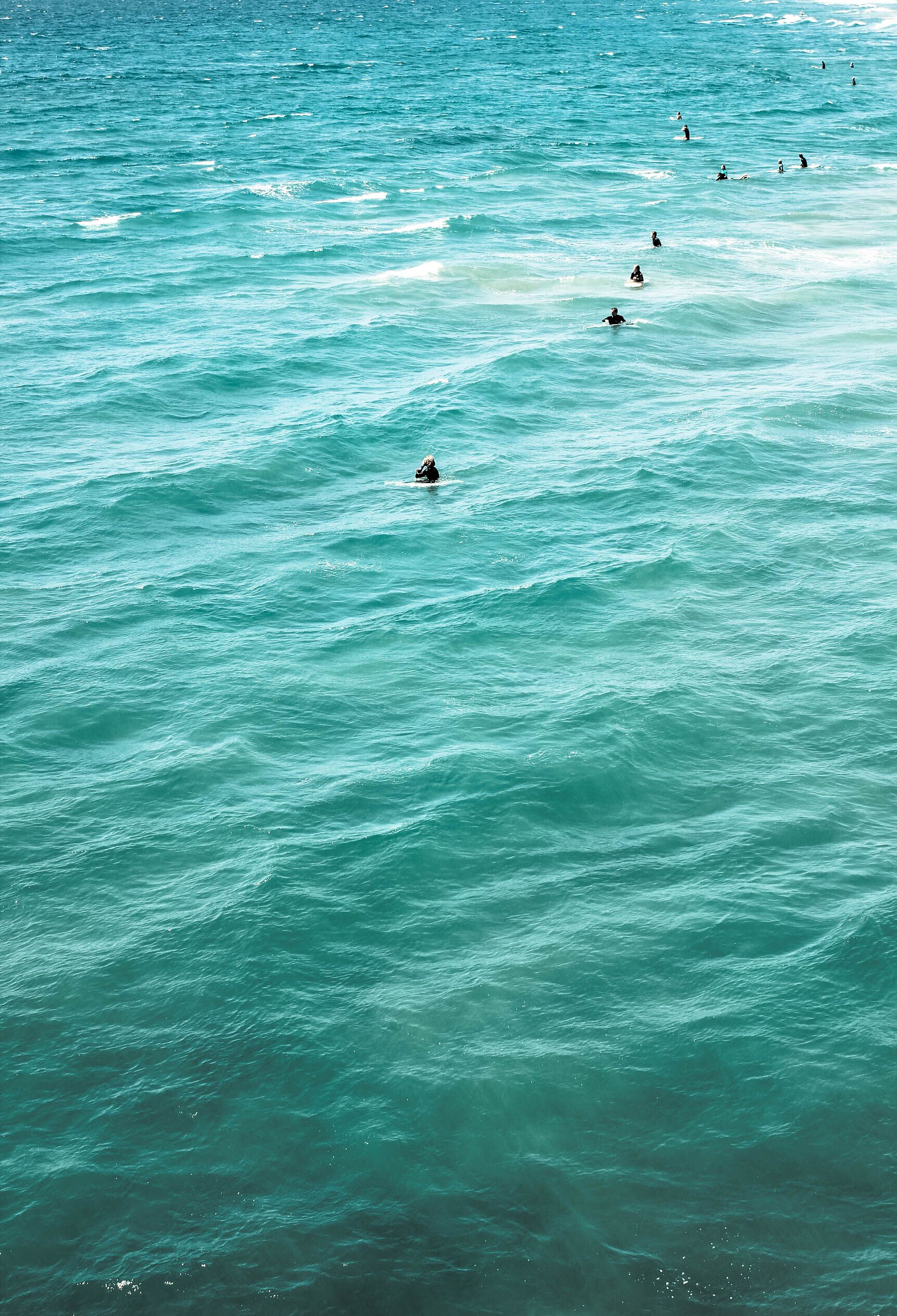Ocean waves with surfers scattered throughout the water in Southern California.