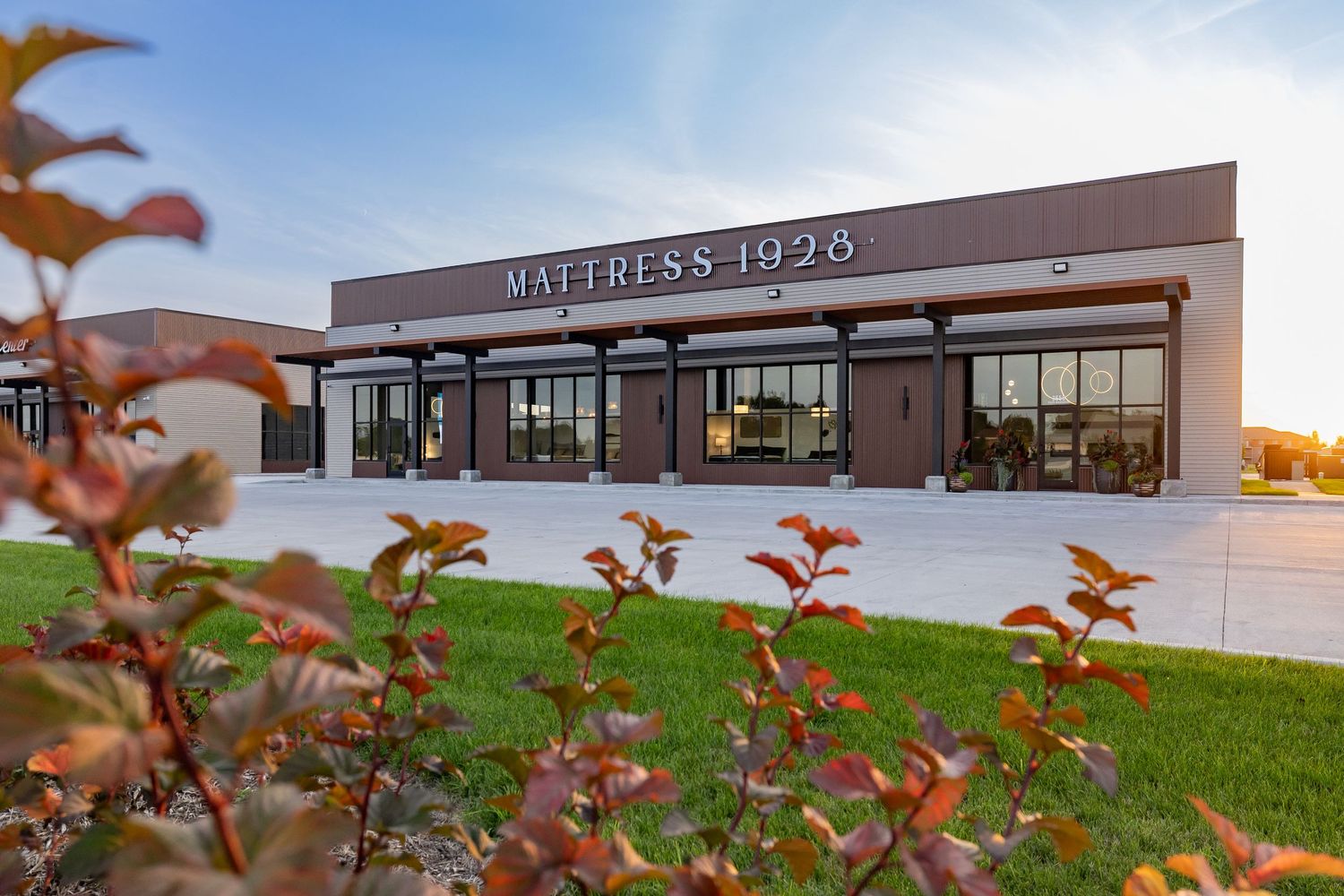 Modern commercial building exterior with red foliage in the foreground.