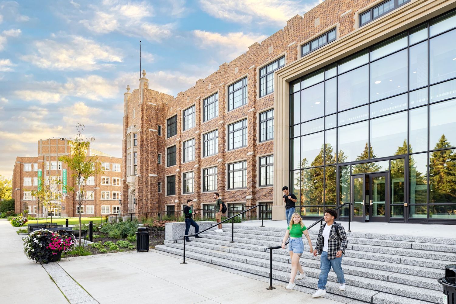 Modern brick educational building with wide concrete steps and large glass windows.