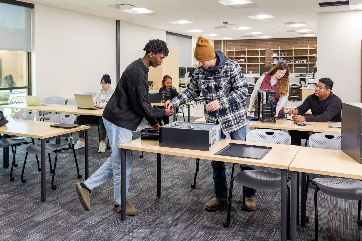 Students working and collaborating in a modern office-style classroom setting.