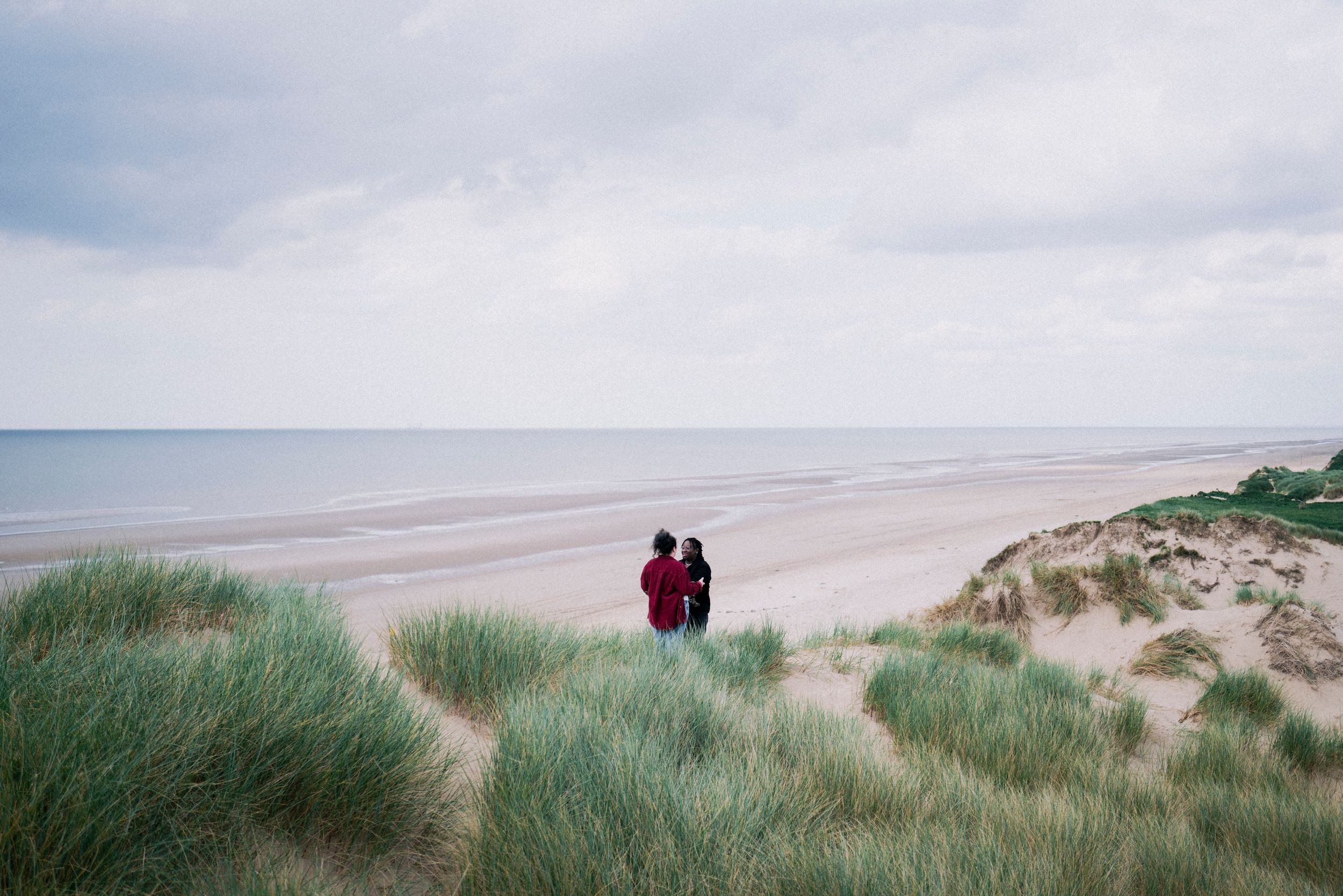 A tender moment captured in the dunes — a soft, timeless and intimate. LGBTQ+ engagement