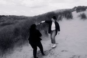Candid black and white photo same sex engagement playing on sandy dunes—capturing joy, movement, and the beauty of carefree moments. lgbtq+