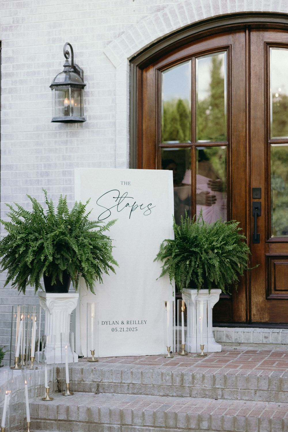 Elegant entrance with wooden door flanked by ferns and wedding signage. The Bradford, Separk  Mansion, Graylyn Estate