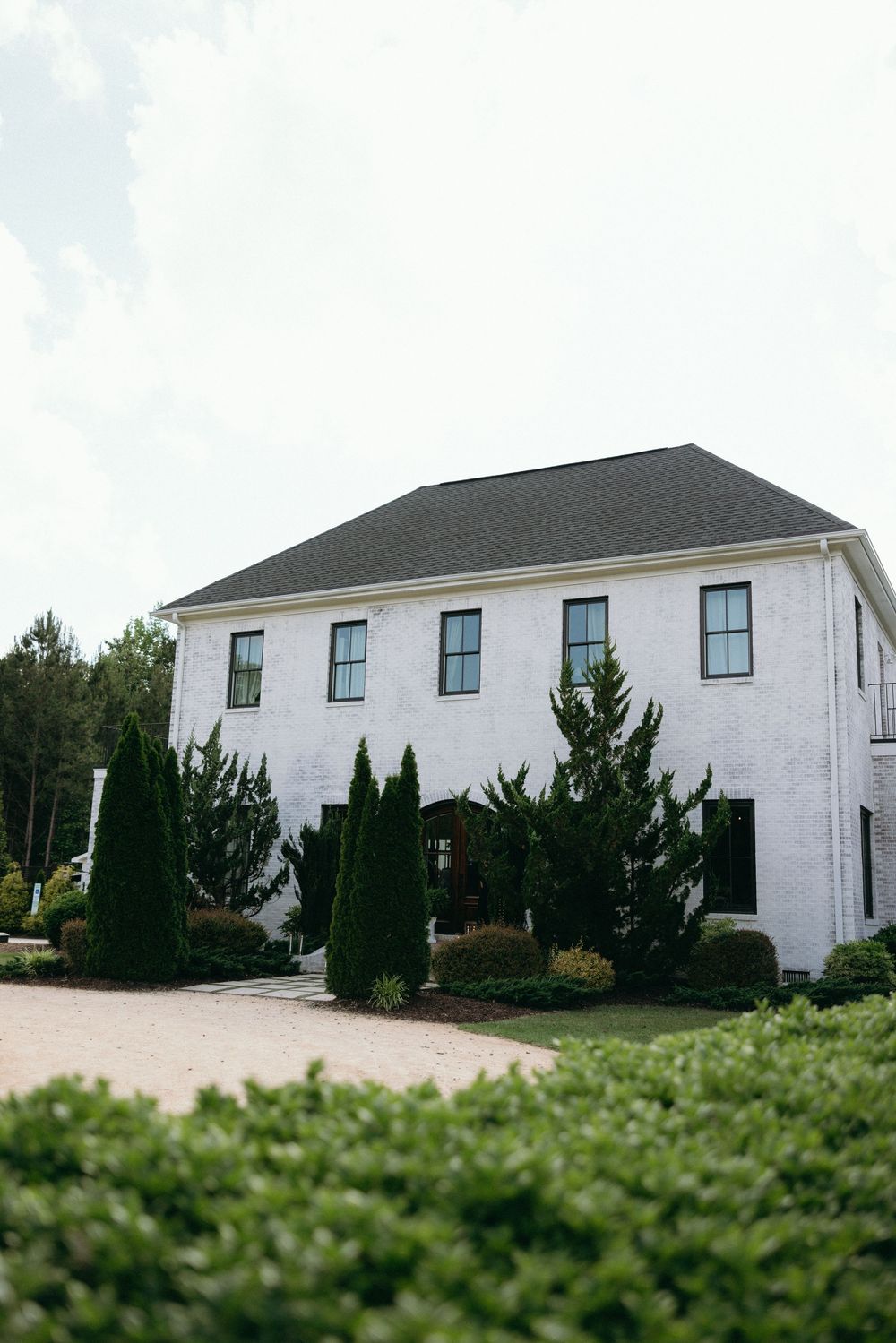 A white two-story house with black windows surrounded by evergreen landscaping. Best wedding photographer in Boone NC
