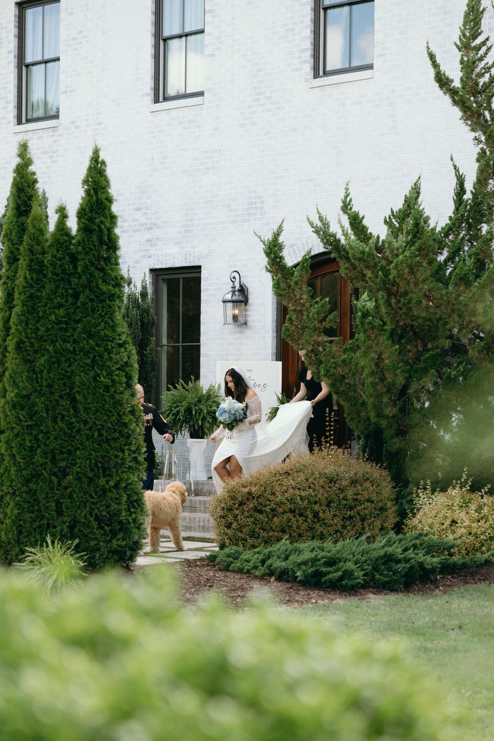 A white building exterior with landscaped greenery and shrubs along the facade. The Bradford, Separk  Mansion, Graylyn Estate