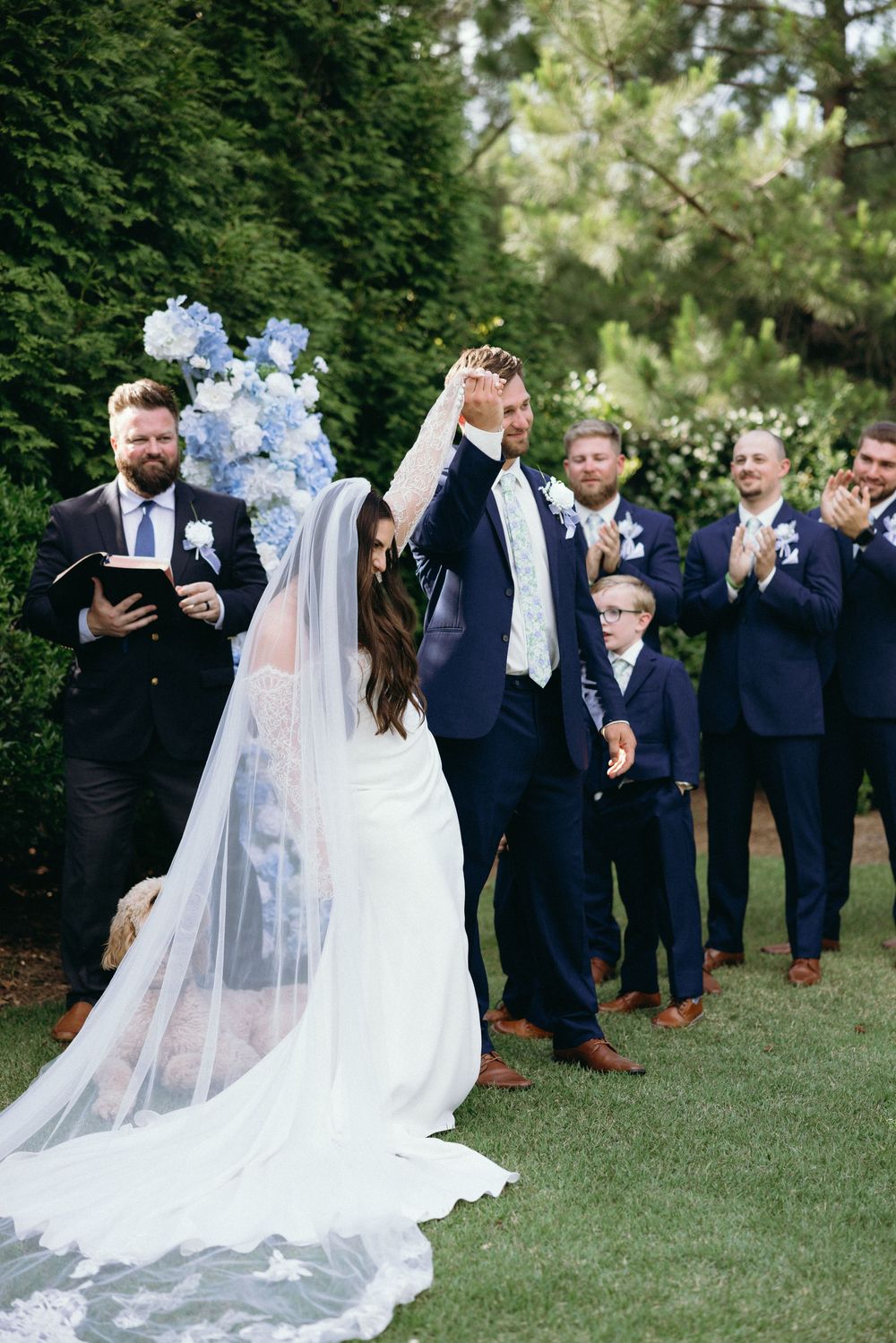 Wedding party poses on a lawn with the bride's flowing white dress and veil. The Bradford, Separk  Mansion, Graylyn Estate