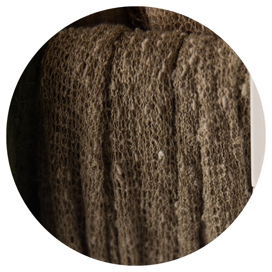 Close-up texture of dark olive green knitted fabric with ribbed pattern and natural fiber details.