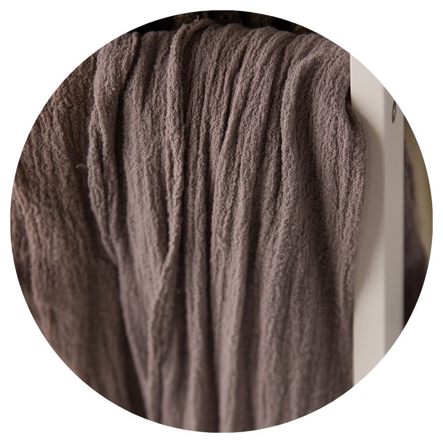 Close-up of soft, textured brown wool yarn strands hanging vertically, showcasing a warm taupe fiber material.
