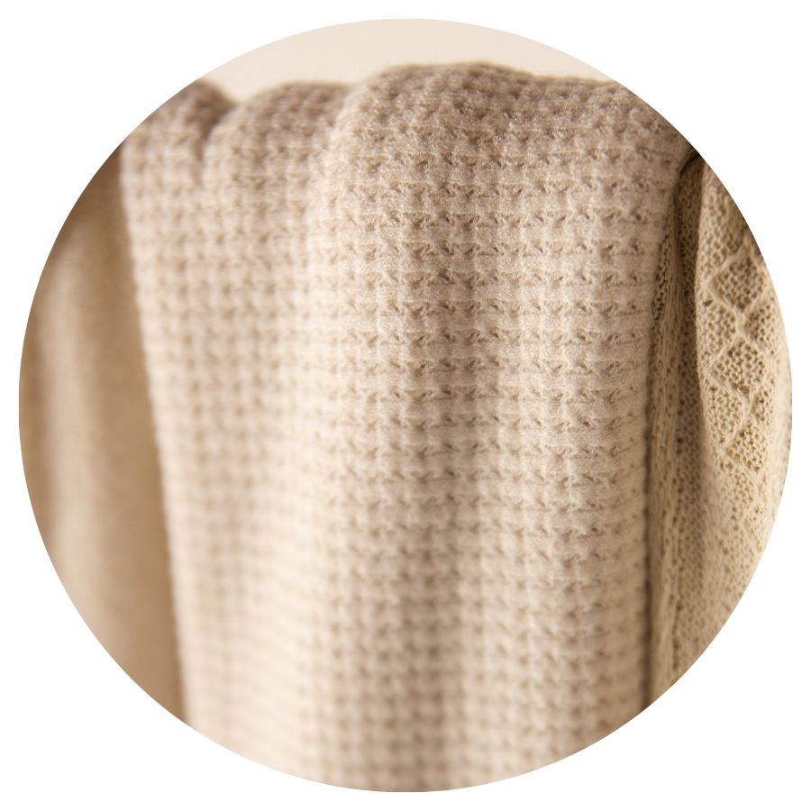 Close-up of a beige waffle-knit textile with a textured pattern, draped softly.