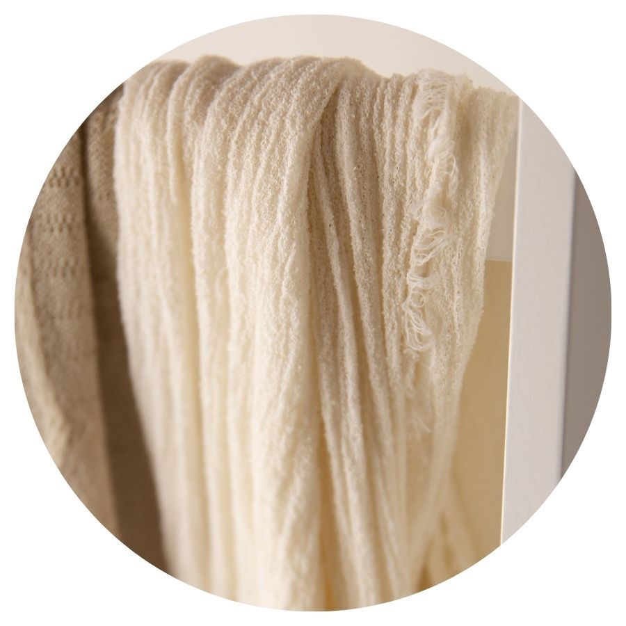 Soft cream-colored yarn hanks hanging to dry, showcasing natural undyed wool fibers in warm ivory tones.