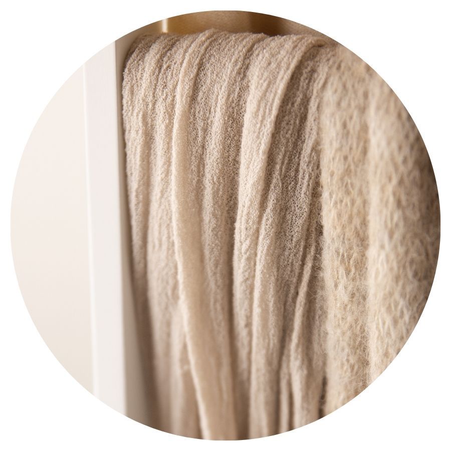 Close-up of soft beige mohair yarn strands hanging loosely in warm neutral tones.