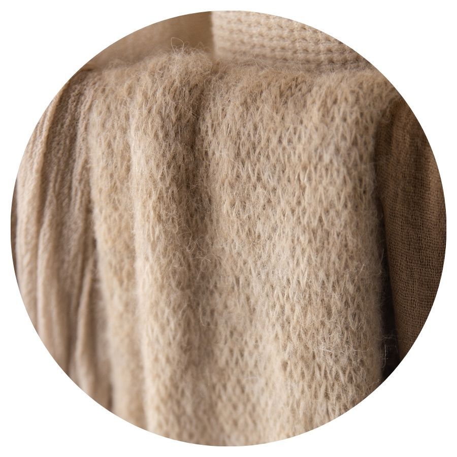 Close-up of soft, fluffy beige knit fabric with a cozy, textured weave pattern.