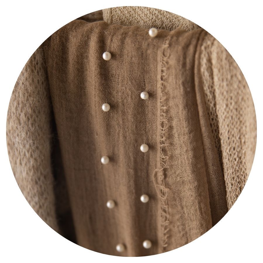 Brown textured knit fabric adorned with pearl embellishments in vertical rows.