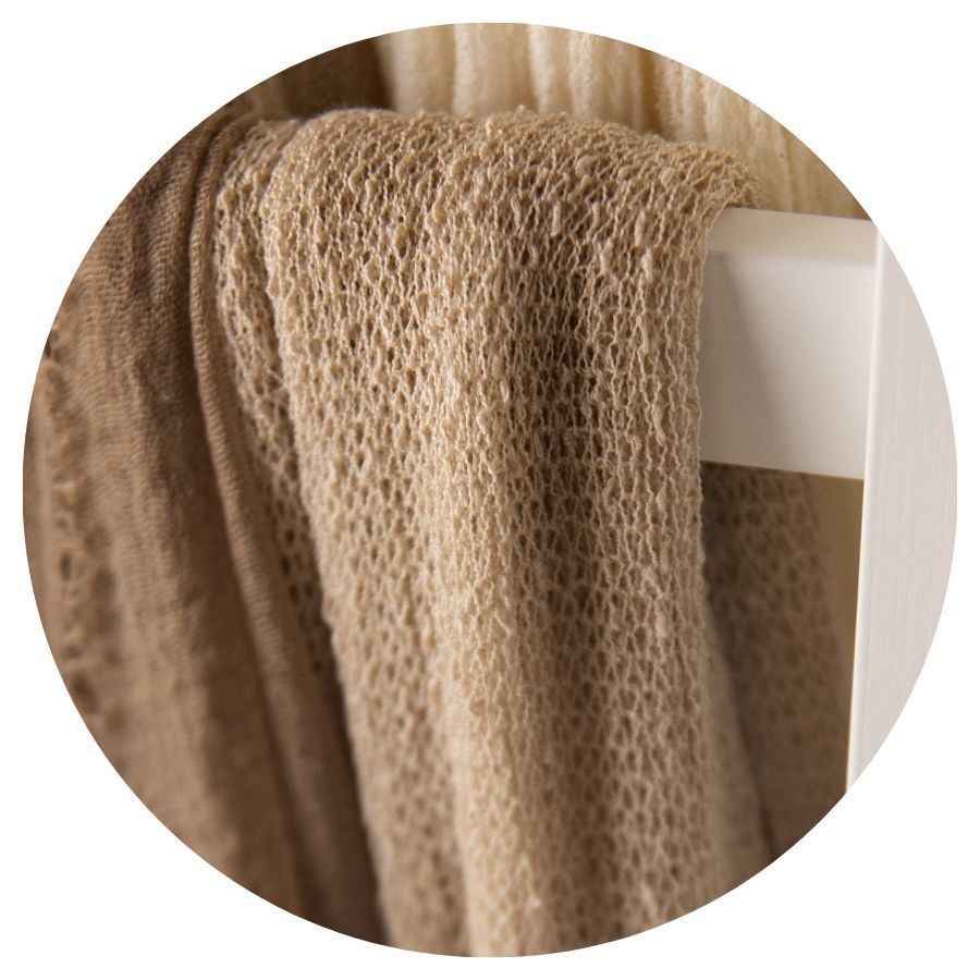 Camel brown open-weave knit fabric draped over a white surface.
