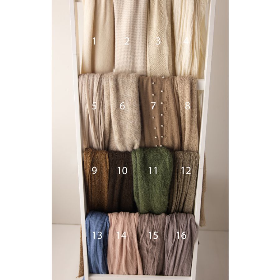 Neatly folded scarves or wraps in neutral tones numbered 1-16, displayed on shelves in beige, brown, green, and blue hues.