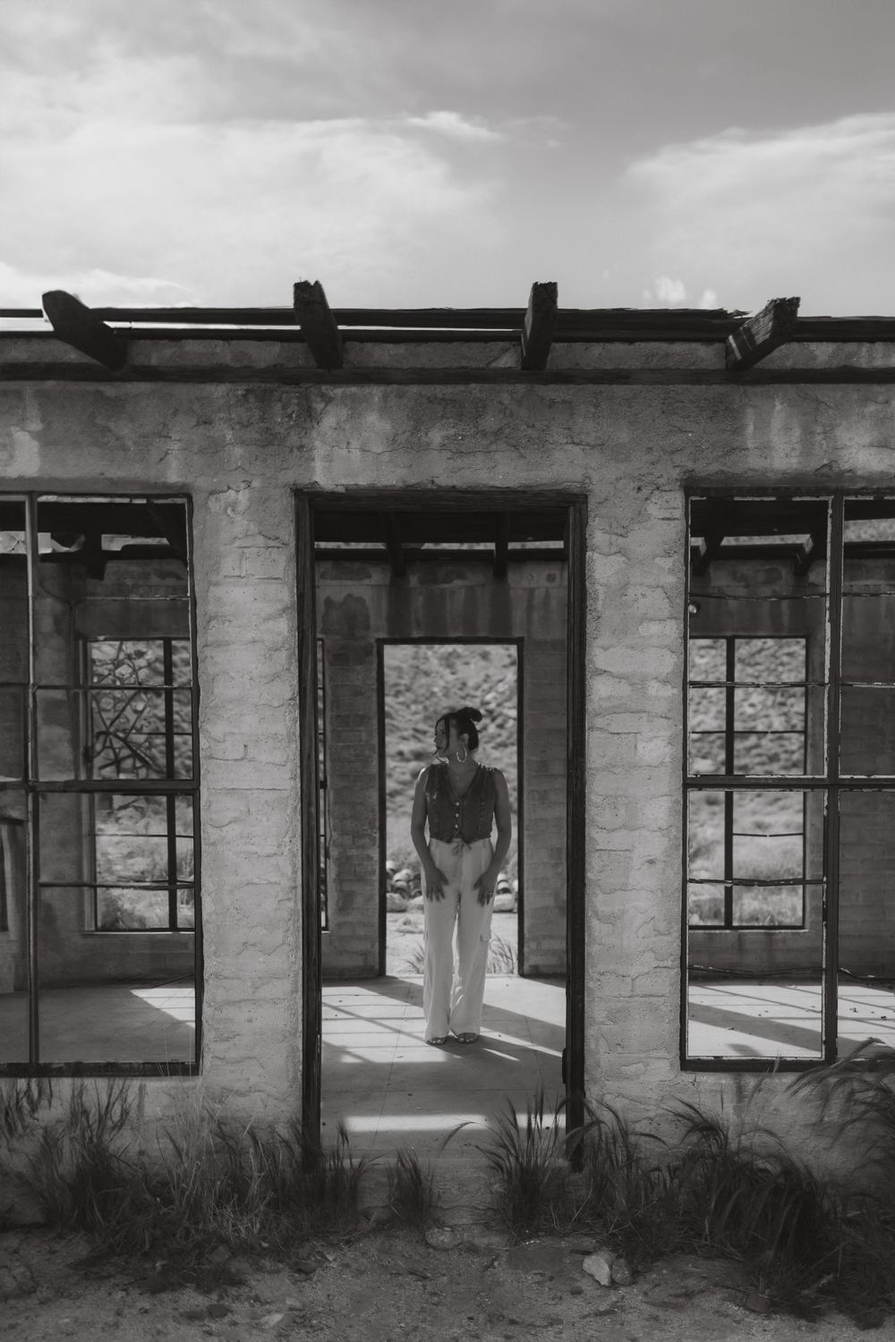 Silhouette in black and white photo standing centered in architectural ruins with desert backdrop.