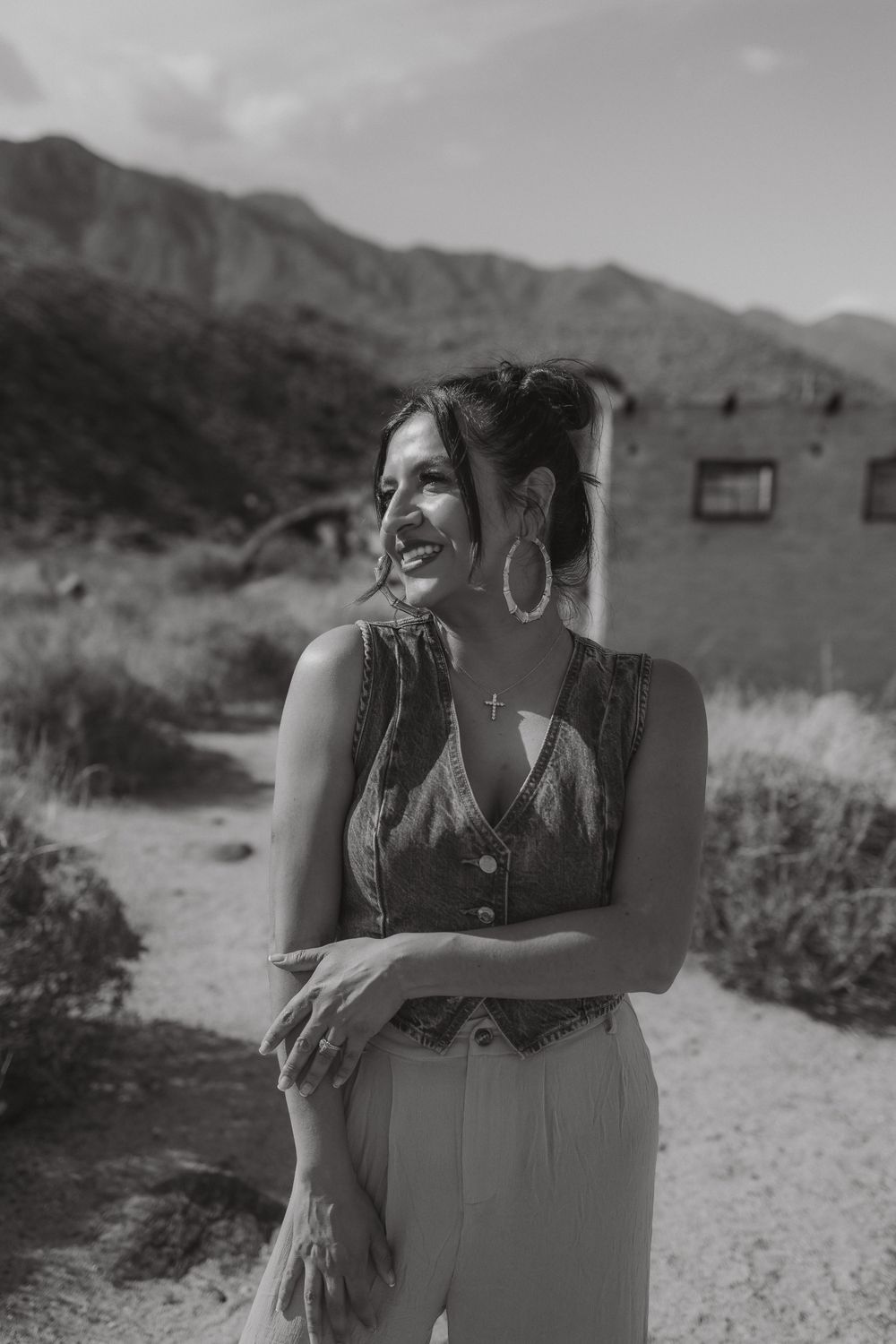 Black and white desert portrait with abandoned building and mountain range in background.