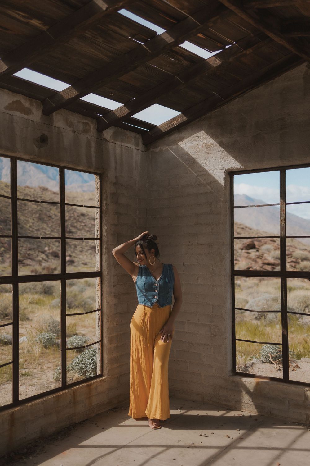A person leans against a concrete pillar in a desert building with dramatic lighting.