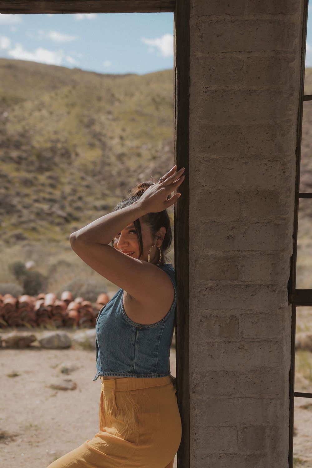 A figure in yellow pants and denim spins gracefully in an abandoned desert structure.