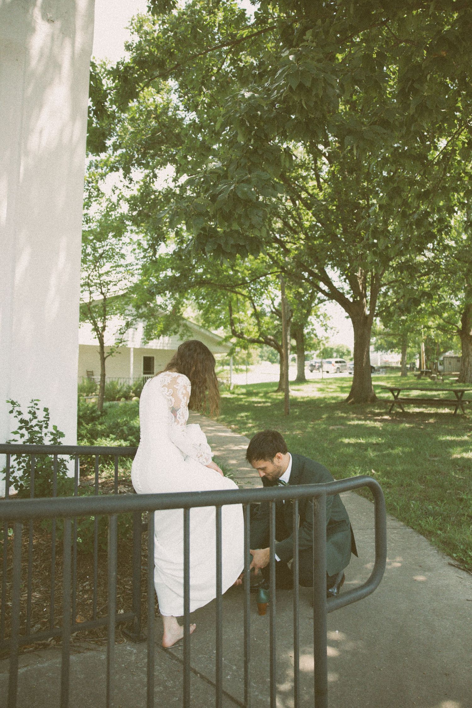 Wedding couple shares playful moment on outdoor staircase railing.