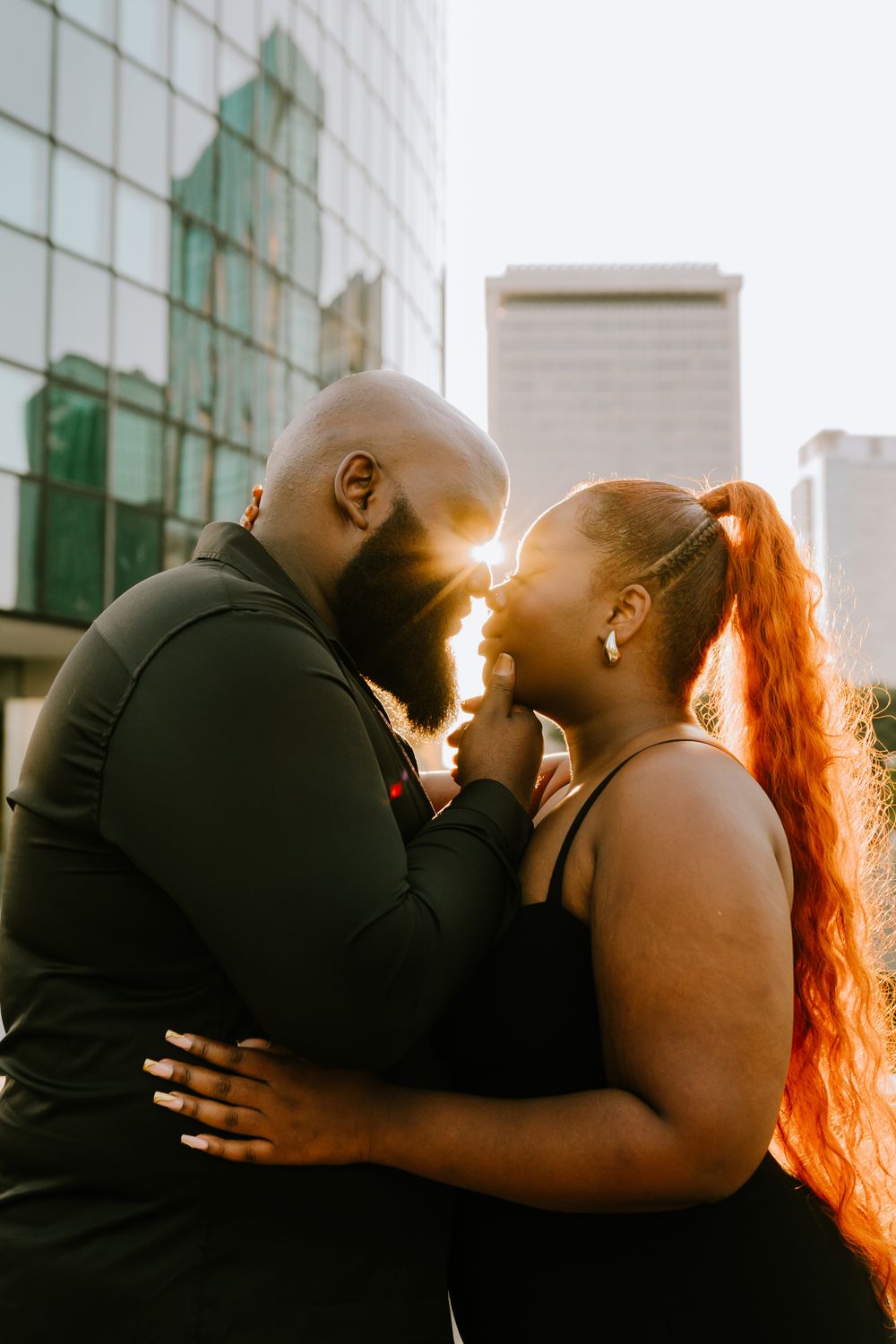 A romantic couple shares an intimate moment against a backdrop of urban architecture.