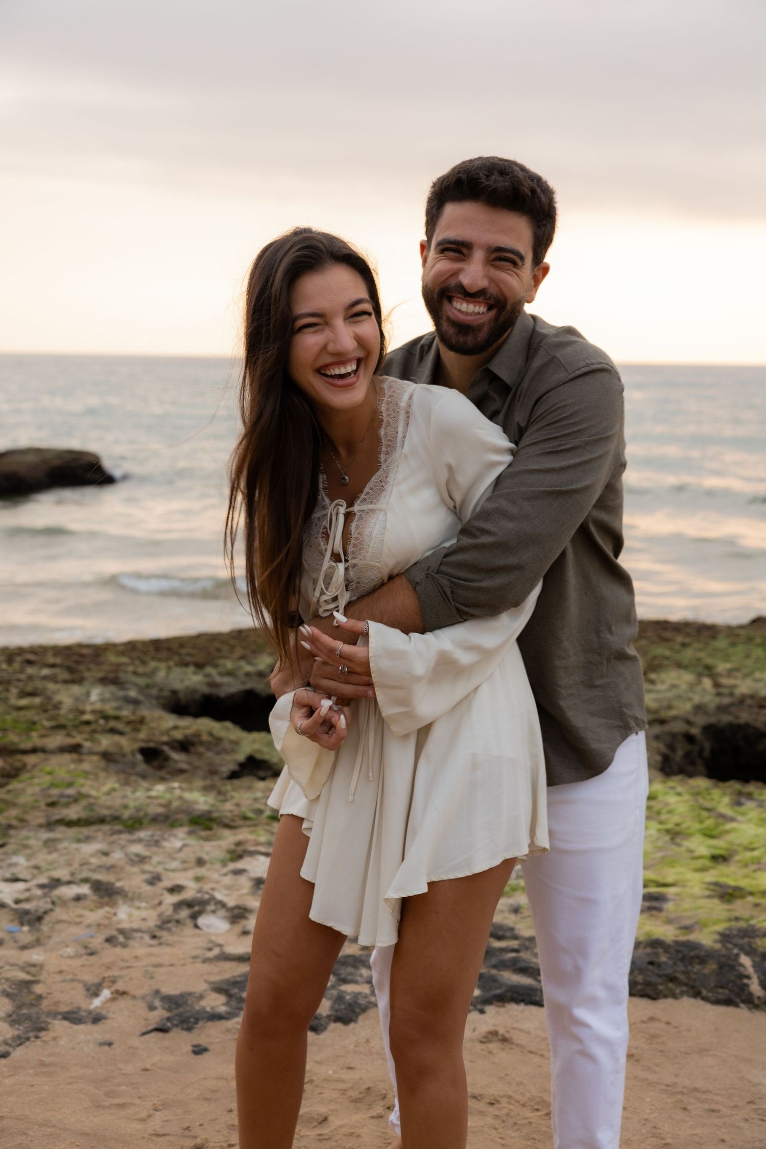 Intimate black and white portrait of a couple embracing, with sunglasses and an engagement ring visible.