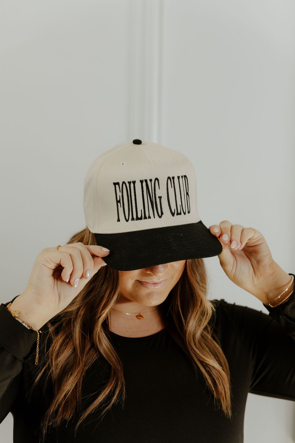 Close-up shots of a white baseball cap with 'Foiling Club' text in black lettering. Hairstylist Branding