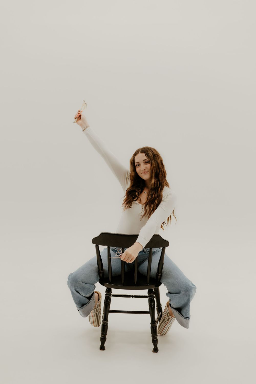 Dynamic poses with a black chair against minimalist white background.