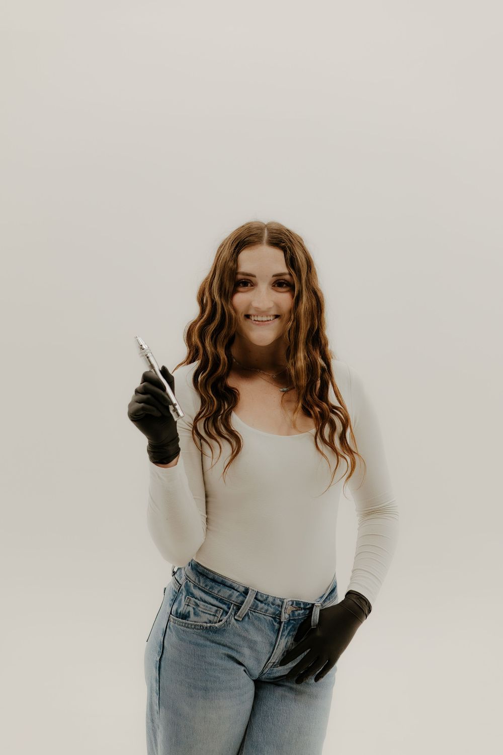 Fashion model wearing white top and jeans with black gloves strikes playful poses.