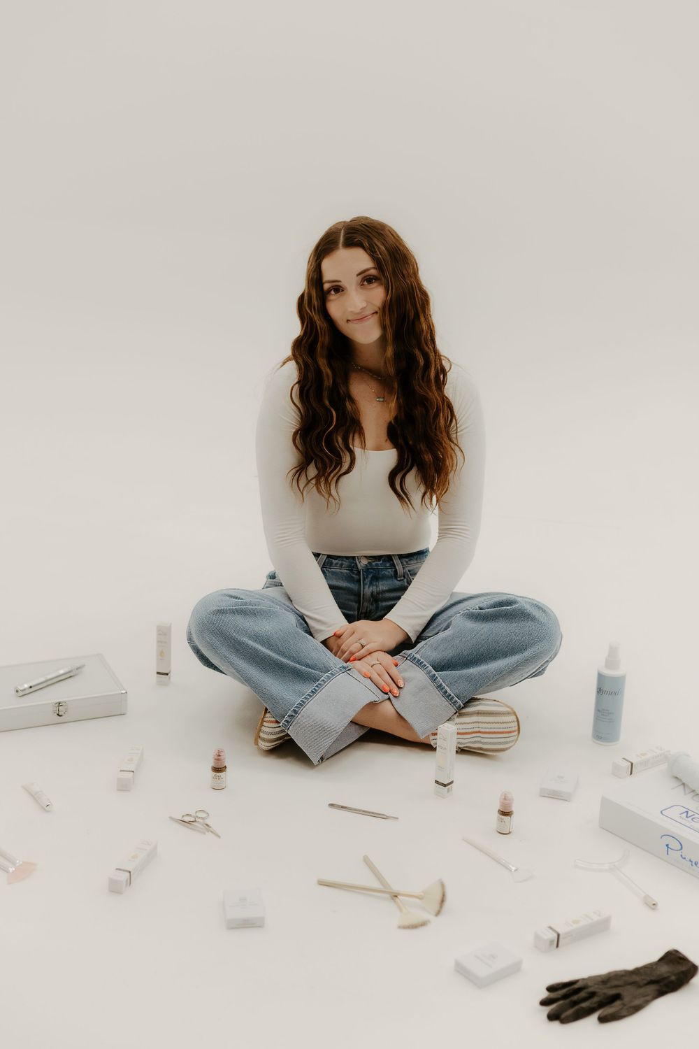 Lifestyle product shot with beauty items and skincare products arranged on white floor.