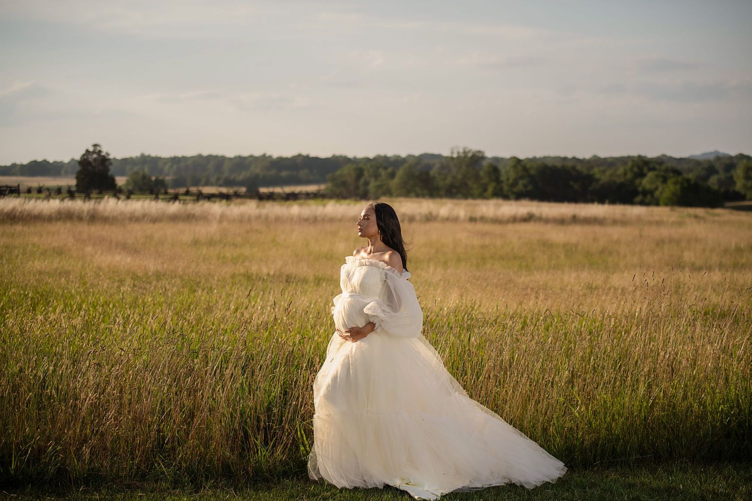 A wedding dress portrait in a golden meadow at sunset capturing an ethereal bridal moment.
