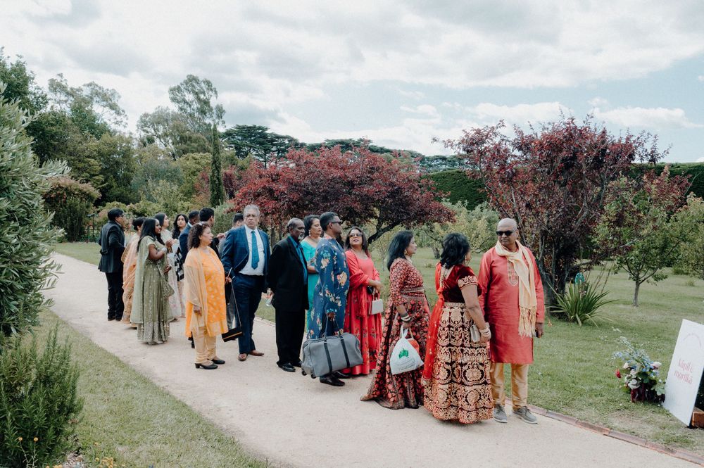 Wedding guests in colorful attire walking along garden path.