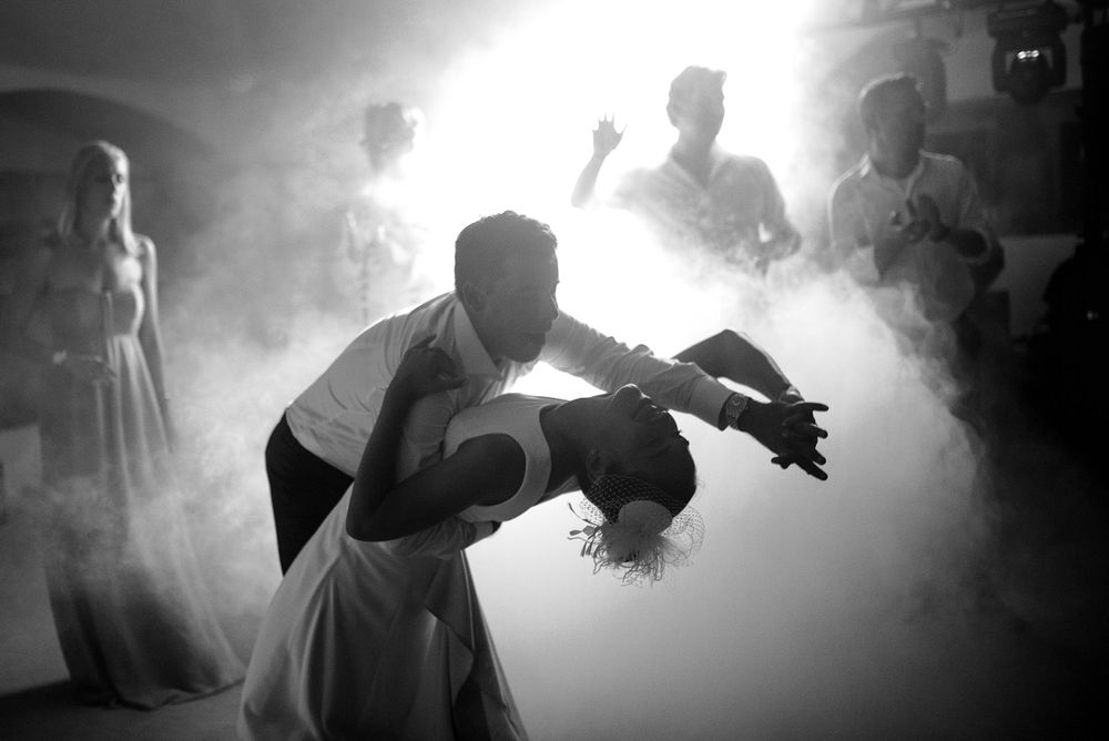 Dramatic black and white dance photo with couple in smoky atmosphere.