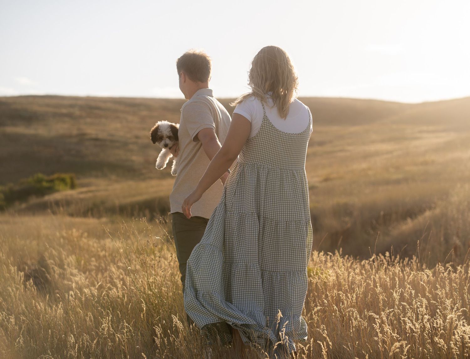 Engagement photo in Cache Valley, Utah, featuring a couple waljing in a scenic outdoor field with the Wellsville Mountains in the background