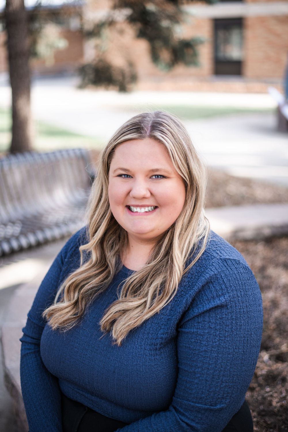 Portrait series of a person in a navy sweater sitting on a bench outdoors.