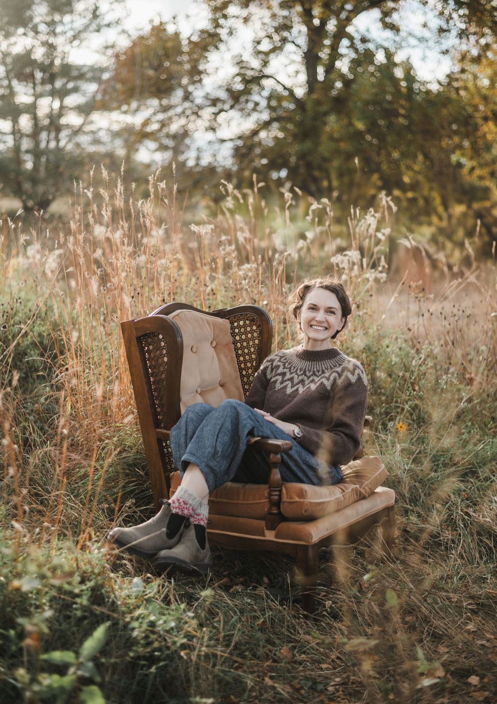 Vintage brown leather couch placed in tall autumn grass during golden hour.