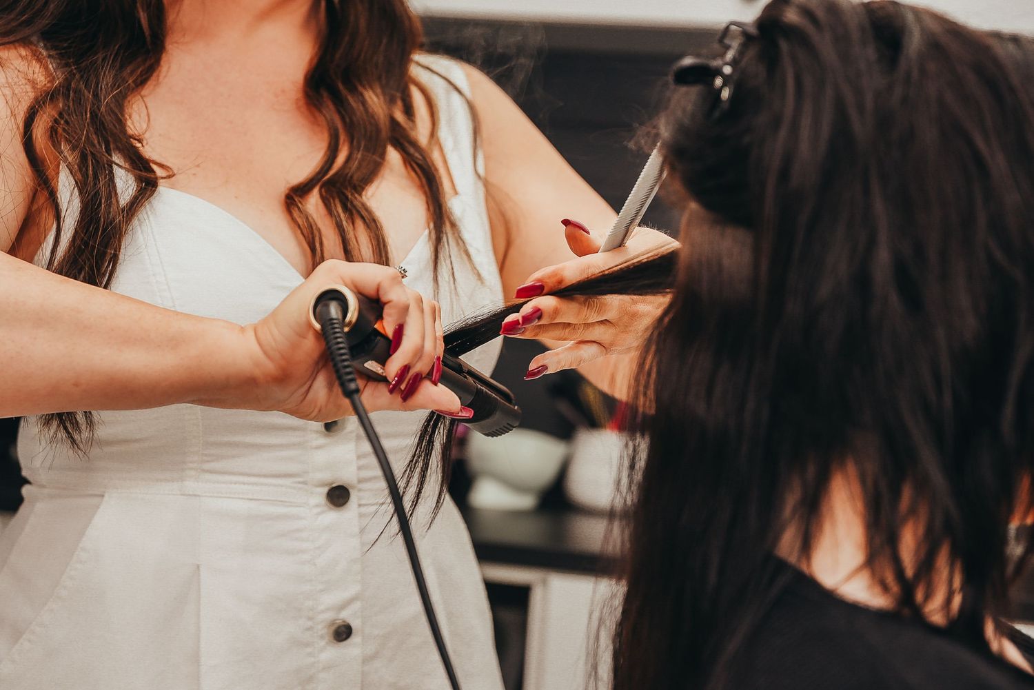 Close-up of hands styling hair with professional tools in salon setting.