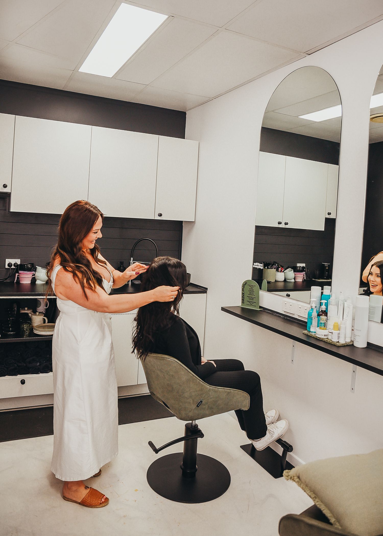 Professional stylist working on client's hair in modern salon setting.